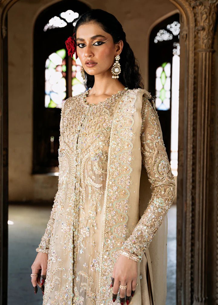 Model wearing an ivory - colored Zarnab dress from Kanwal Malik's Sajni II Formal Collection, adorned with intricate embellishments. Pakistani wedding clothes available online in the UK.
