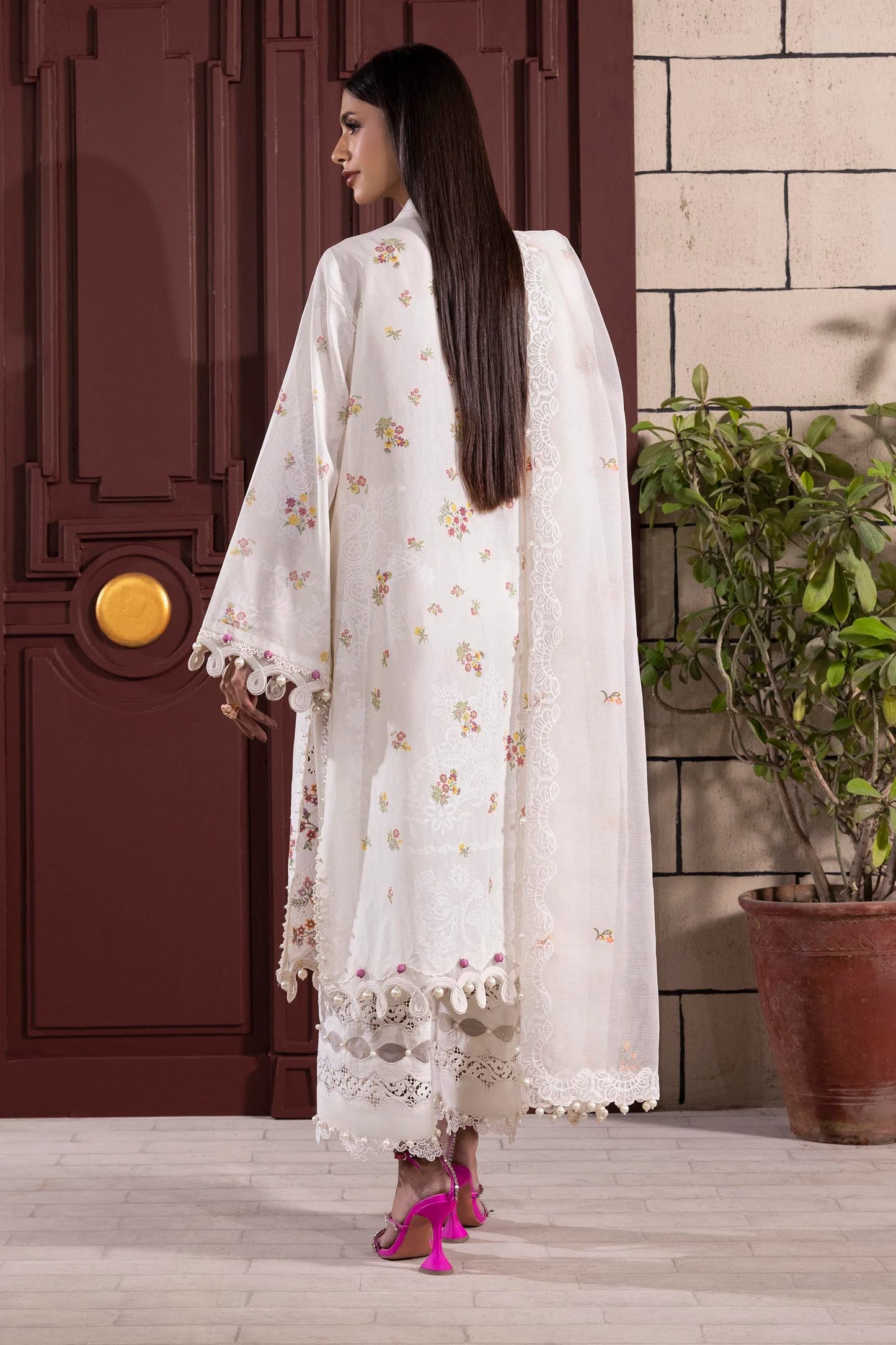 Model wearing white embroidered dress with multicolor floral accents and lace detailing from Sana Safinaz Muzlin Spring '25, Pakistani clothes online UK.
