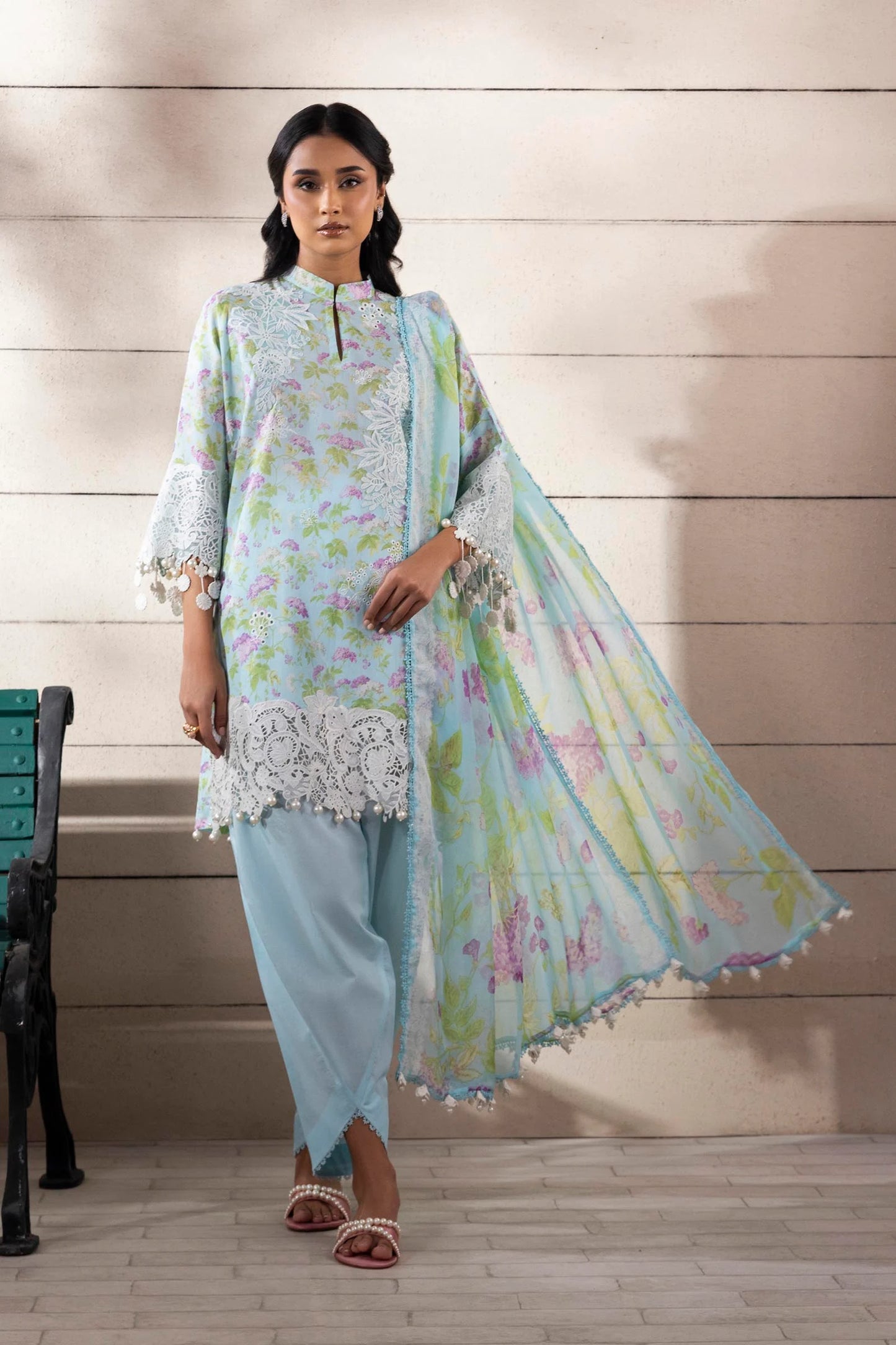 Model wearing aqua blue floral printed dress with white lace detailing from Sana Safinaz Muzlin Spring '25, Pakistani clothes online UK.