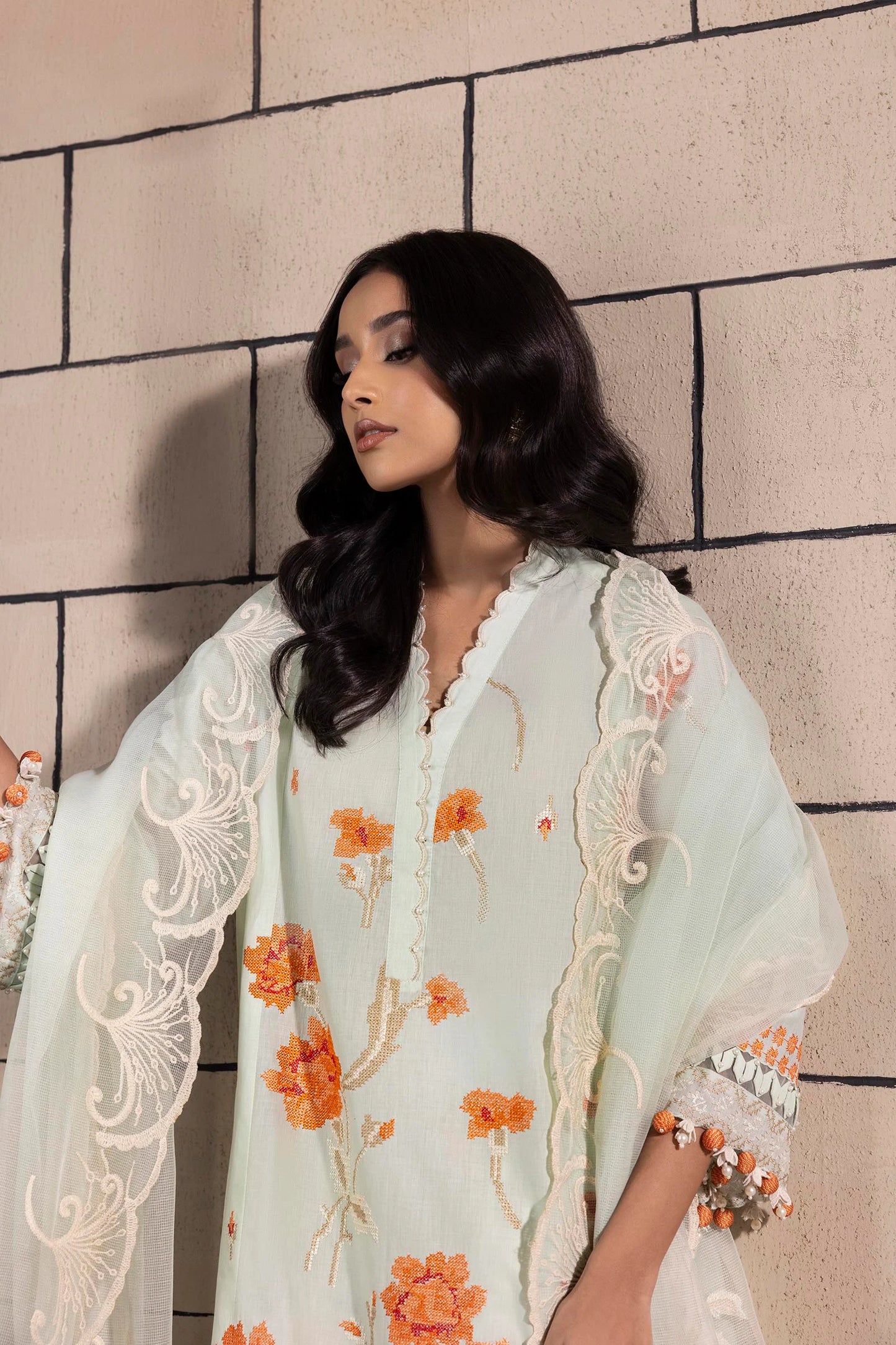 Model wearing mint green dress with orange floral embroidery and matching dupatta from Sana Safinaz Muzlin Spring '25, Pakistani Luxury pret UK.