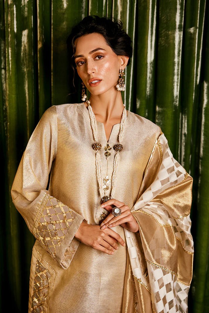 Model wearing a golden Basanti outfit from Mushq with intricate gota detailing, showcasing Pakistani designer clothes online in the UK, perfect for weddings.