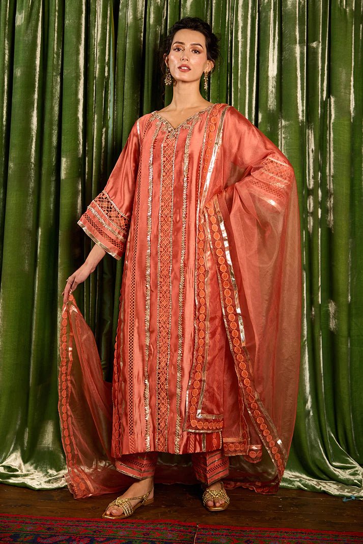 Model wearing a vibrant orange Rajputani Rani outfit from Mushq with intricate gota work, ideal for Pakistani weddings, available online in the UK.