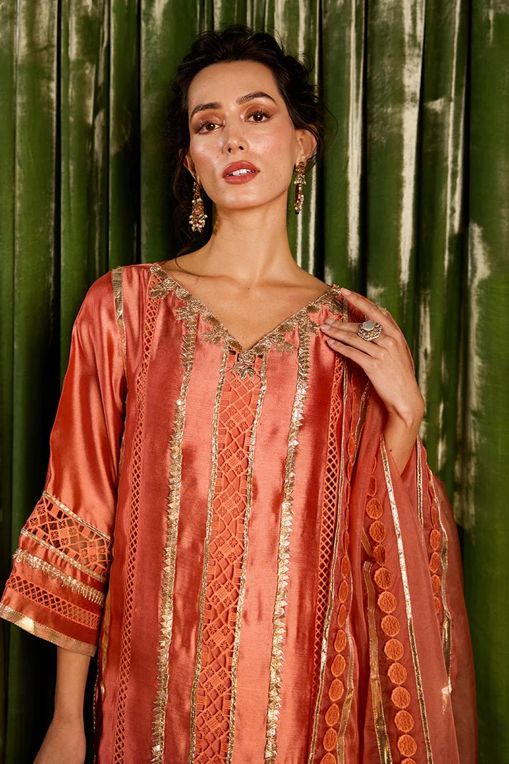 Model wearing a vibrant orange Rajputani Rani outfit from Mushq with intricate gota work, ideal for Pakistani weddings, available online in the UK.