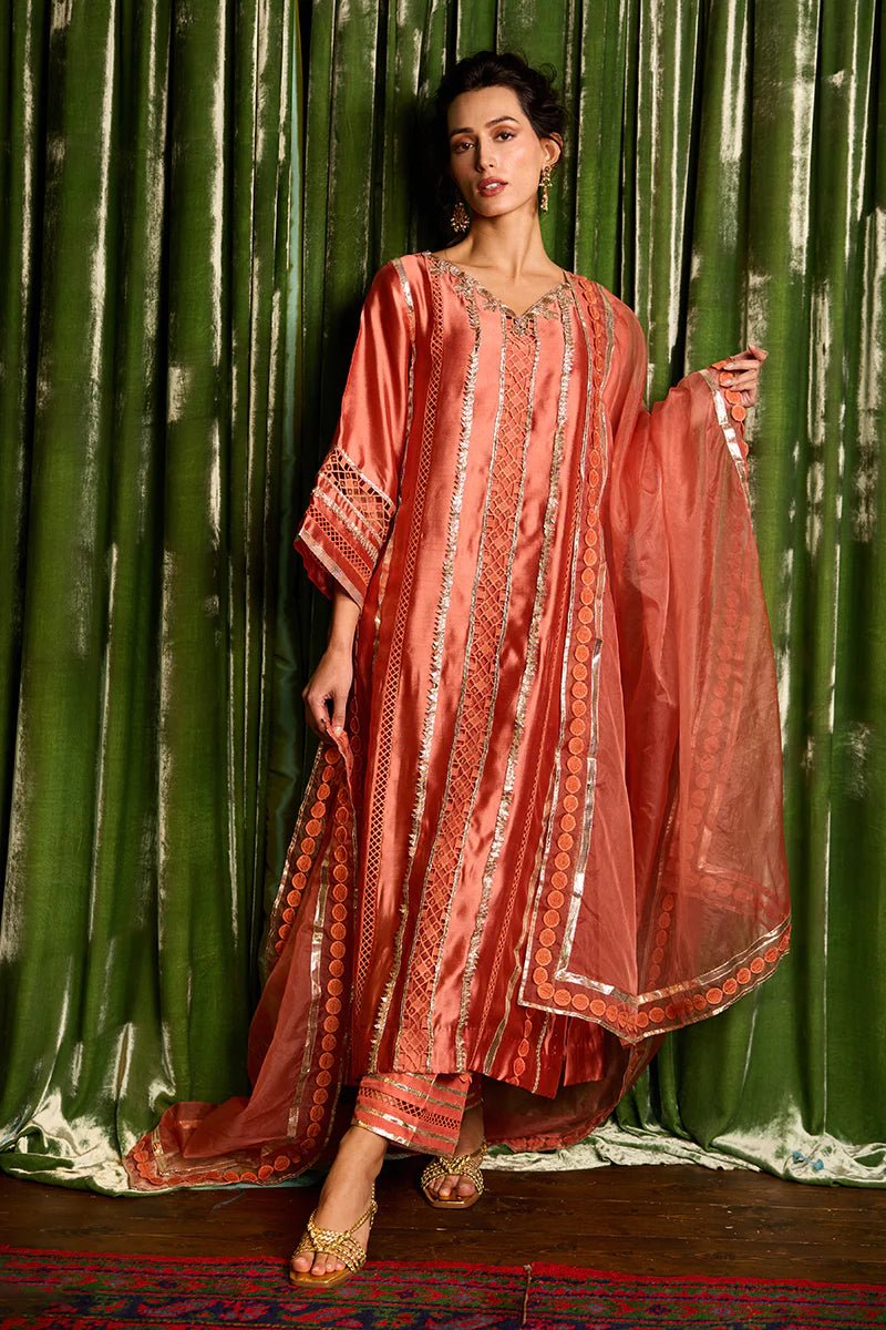 Model wearing a vibrant orange Rajputani Rani outfit from Mushq with intricate gota work, ideal for Pakistani weddings, available online in the UK.