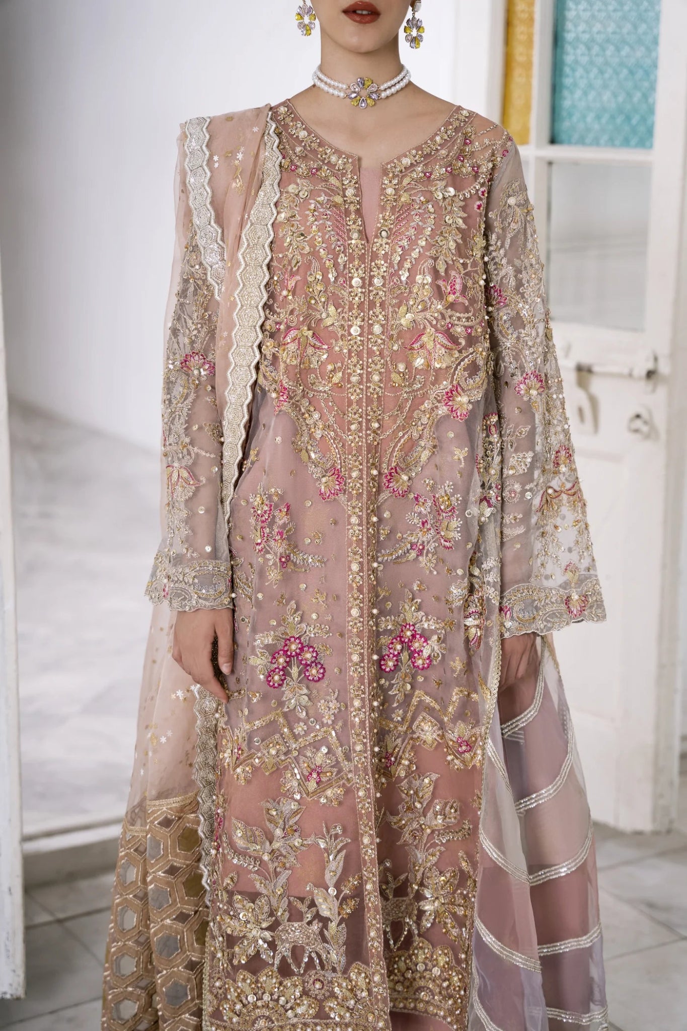 Model wearing a pastel pink LUBNA dress with intricate embroidery and embellishments, from Mysie by Tahira. Find Pakistani clothes online in UK, perfect for weddings.