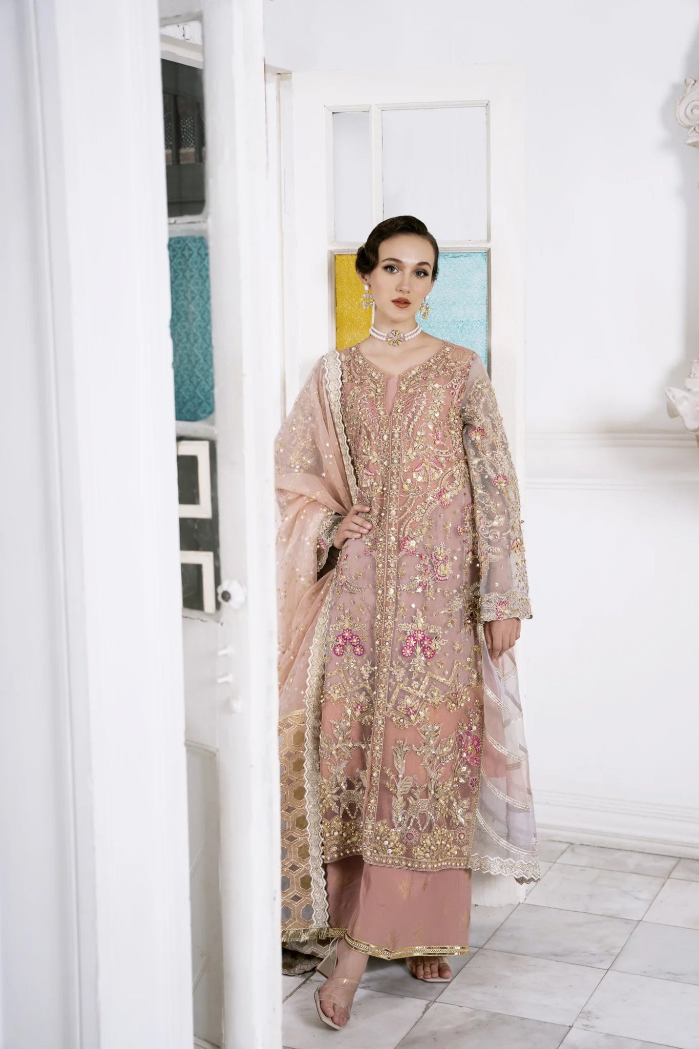 Model wearing a pastel pink LUBNA dress with intricate embroidery and embellishments, from Mysie by Tahira. Find Pakistani clothes online in UK, perfect for weddings.