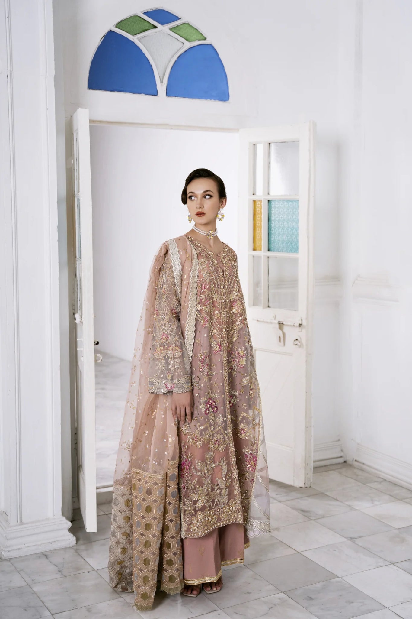 Model wearing a pastel pink LUBNA dress with intricate embroidery and embellishments, from Mysie by Tahira. Find Pakistani clothes online in UK, perfect for weddings.
