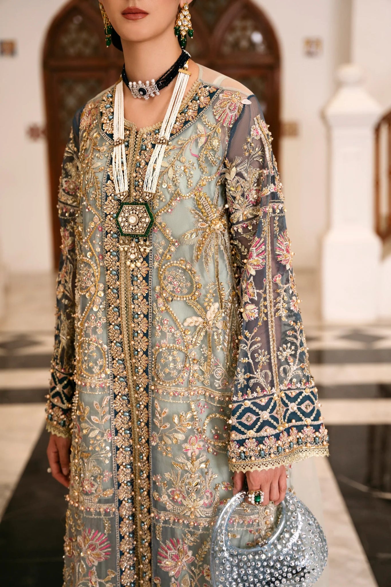 Model wearing a teal and gold RAVEENA dress from Mysie by Tahira, featuring intricate embroidery and a full - length design. Perfect for weddings and special occasions.