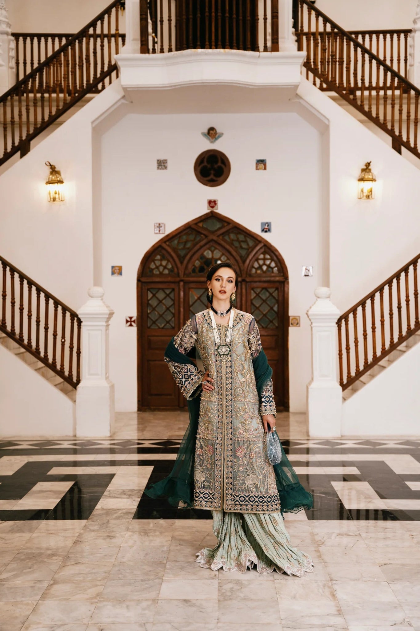 Model wearing a teal and gold RAVEENA dress from Mysie by Tahira, featuring intricate embroidery and a full - length design. Perfect for weddings and special occasions.