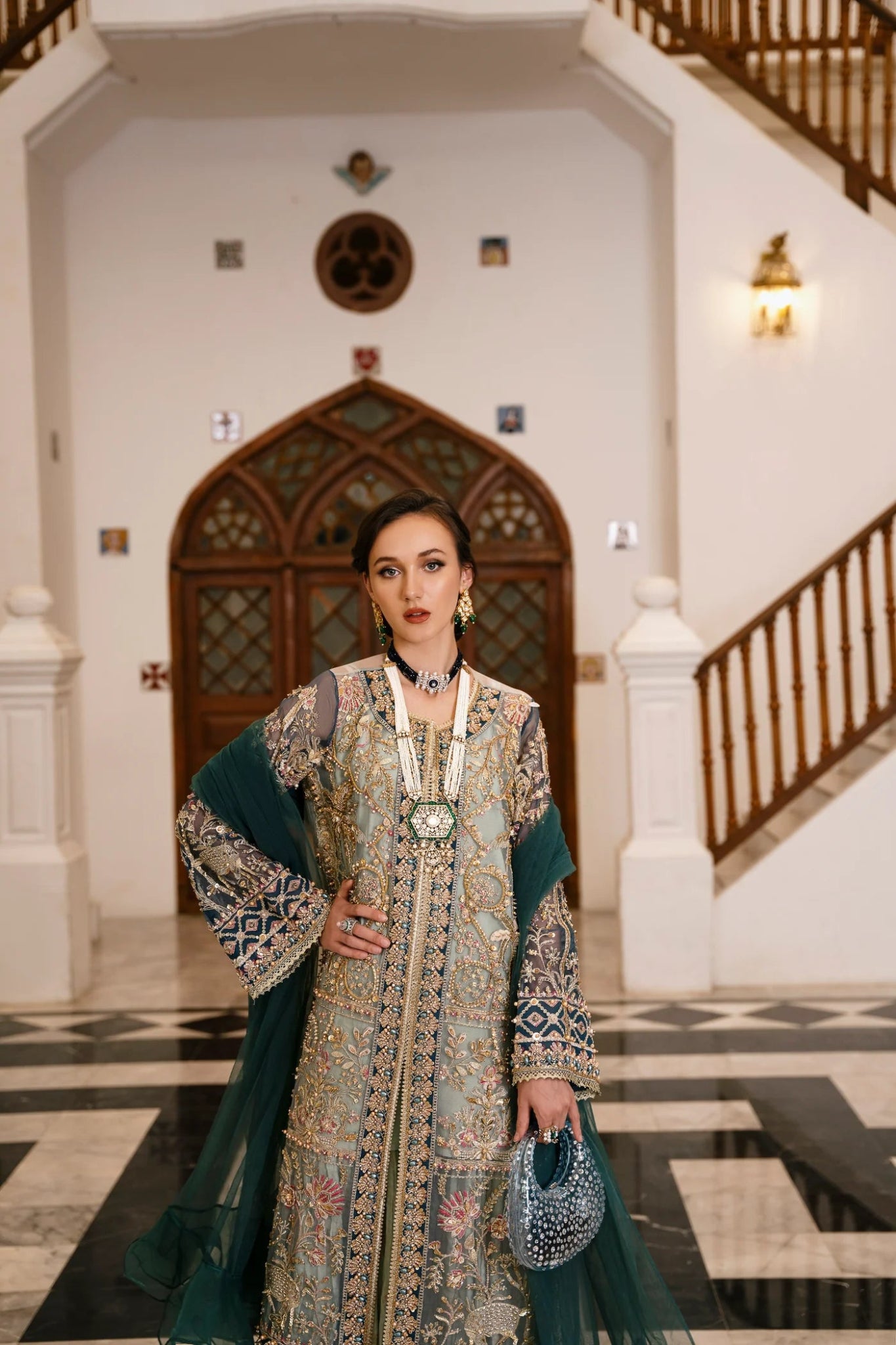 Model wearing a teal and gold RAVEENA dress from Mysie by Tahira, featuring intricate embroidery and a full - length design. Perfect for weddings and special occasions.