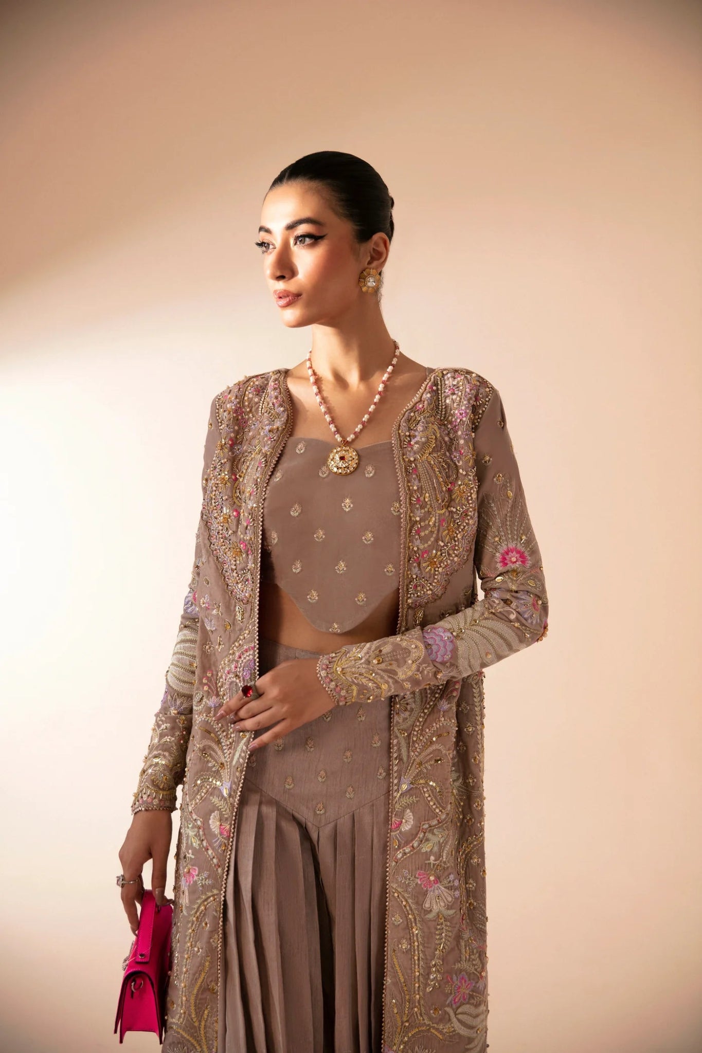 Model wearing FA'IA from Mysie by Tahira in taupe, featuring a pleated skirt and embellished jacket. Pakistani clothes online in UK, ideal for weddings and formal occasions.