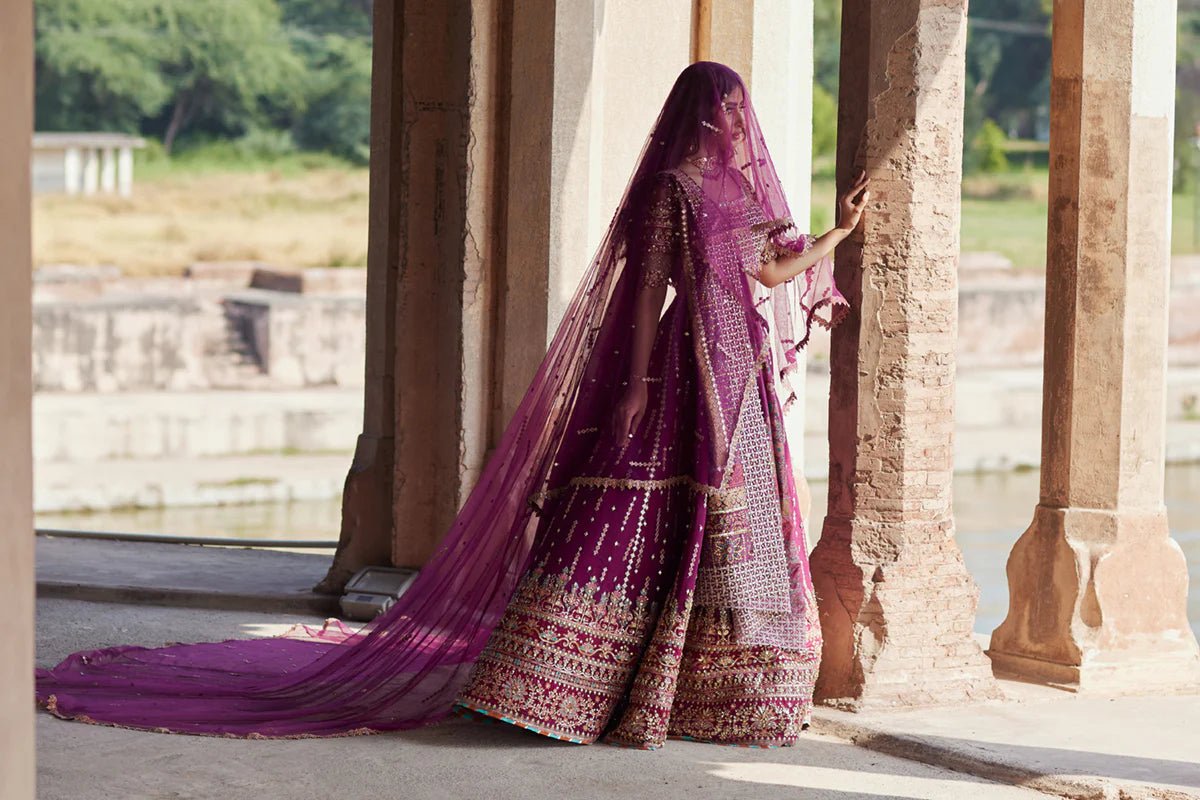 Model wearing Qalamkaar Shadmani Luxury Formals '24 Alya SH - 04 dress in deep magenta with intricate gold embellishments. Shop Pakistani bridal dresses online in the UK now.