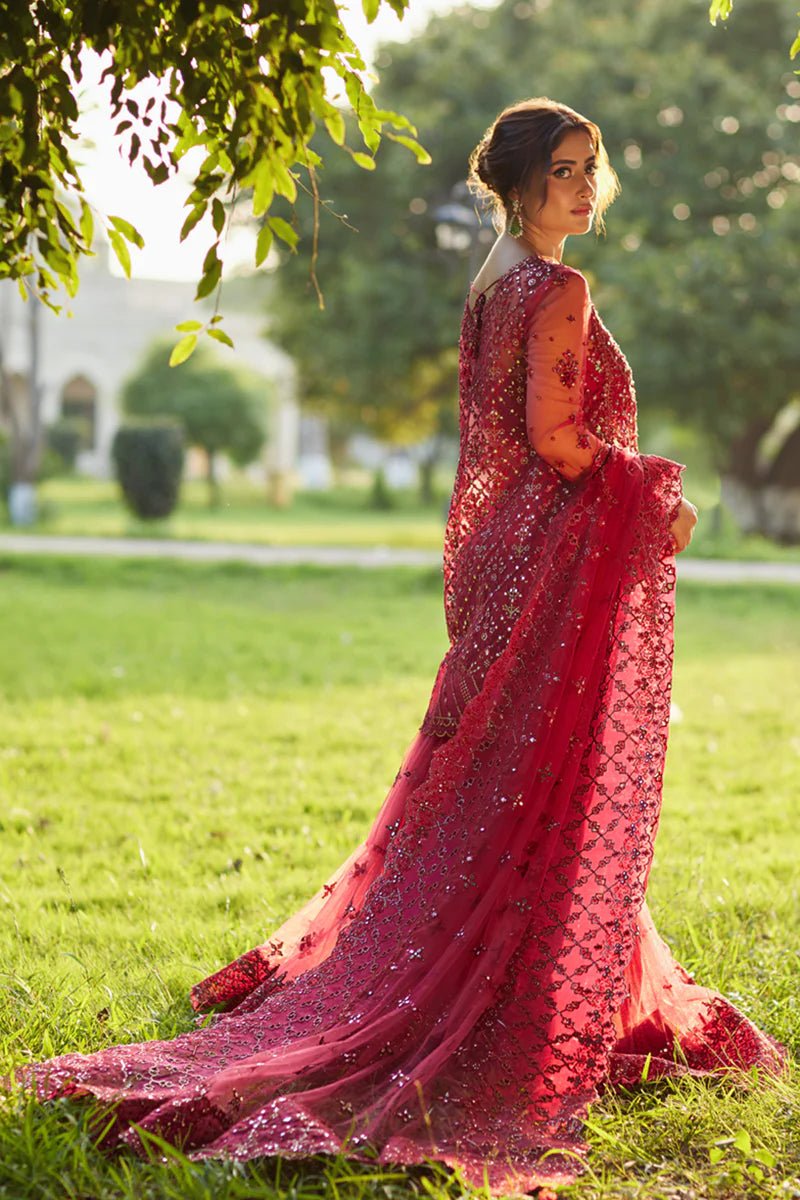 Model wearing Qalamkaar Shadmani Luxury Formals '24 Nurah SH - 07 dress in deep red with intricate gold embellishments. Shop Pakistani bridal dresses online in the UK now.