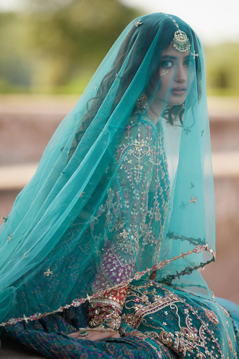 Model wearing Qalamkaar Shadmani Luxury Formals '24 Sama SH - 03 dress in teal with intricate gold embroidery. Shop Pakistani bridal dresses online in the UK now.