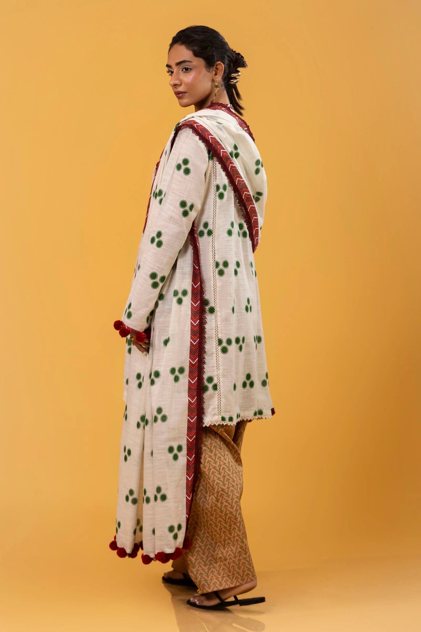 Model wearing Sana Safinaz Mahay Winter '24, showcasing a white and yellow with hues of green 3 - piece outfit with embroidery and intricate printing, ideal for winter casual pret. Available online in the UK.