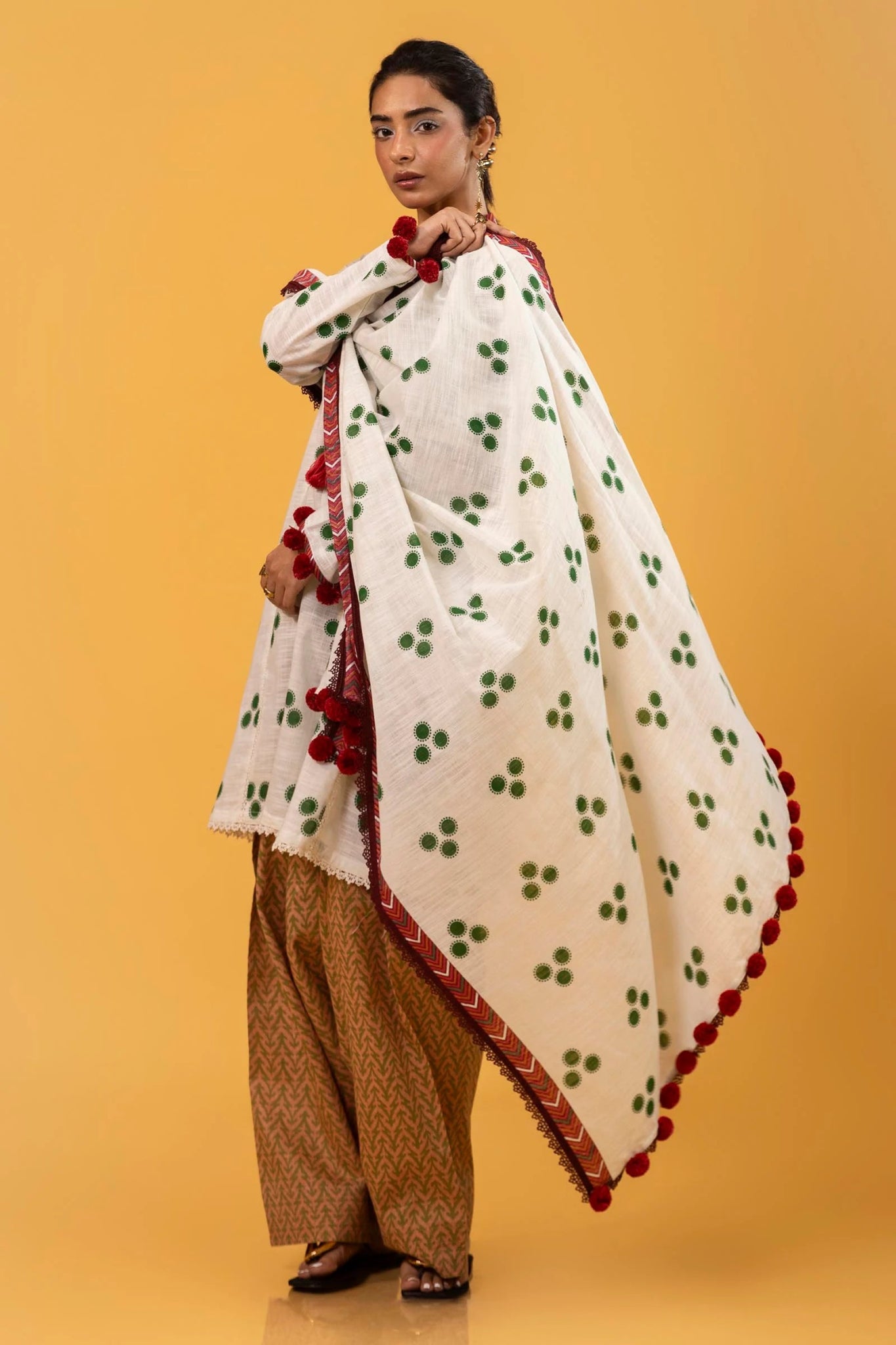 Model wearing Sana Safinaz Mahay Winter '24, showcasing a white and yellow with hues of green 3 - piece outfit with embroidery and intricate printing, ideal for winter casual pret. Available online in the UK.