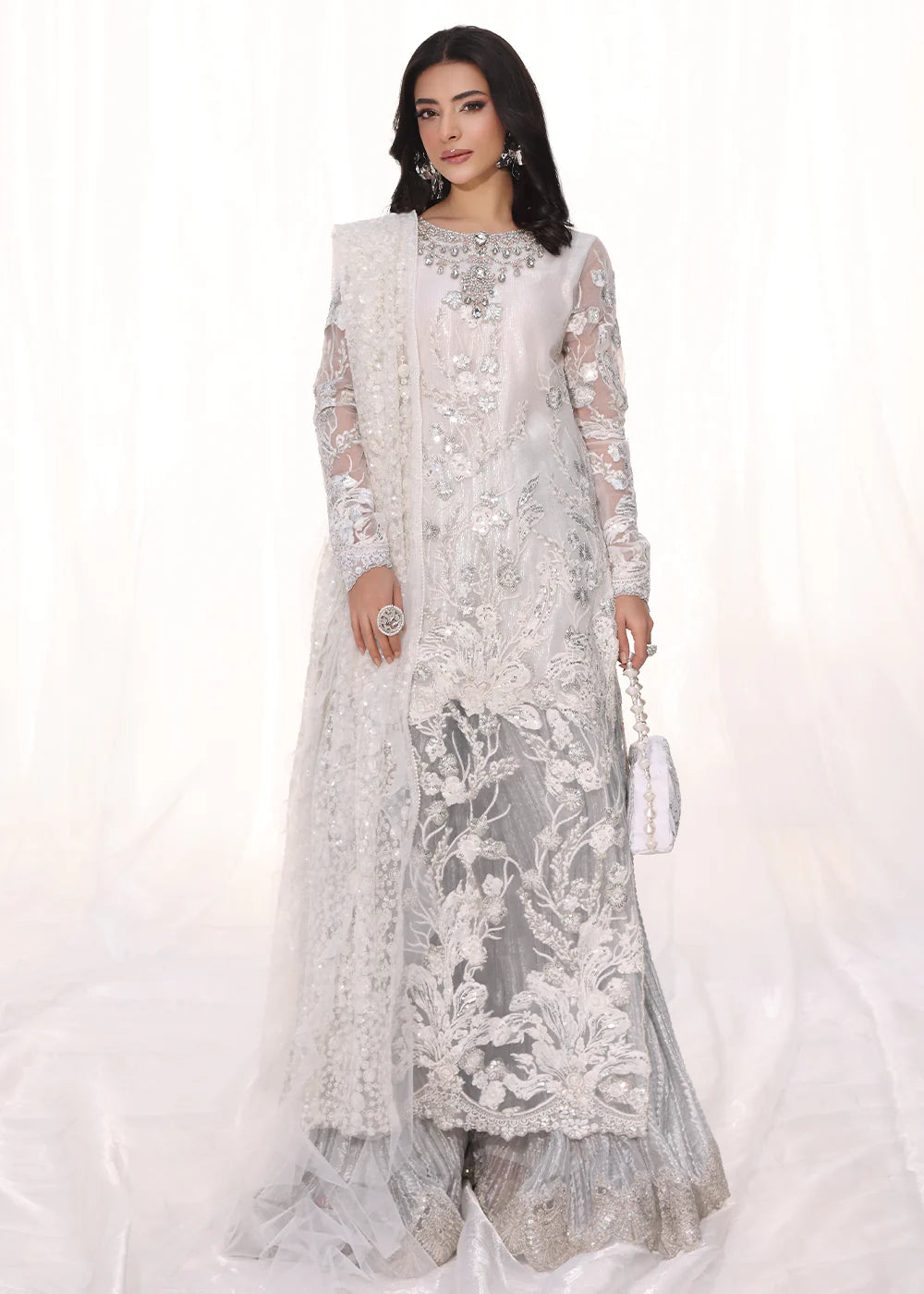 Model wearing silver and white embroidered dress with net dupatta from Musferah Saad Starlit, Pakistani Luxury pret available online in UK.