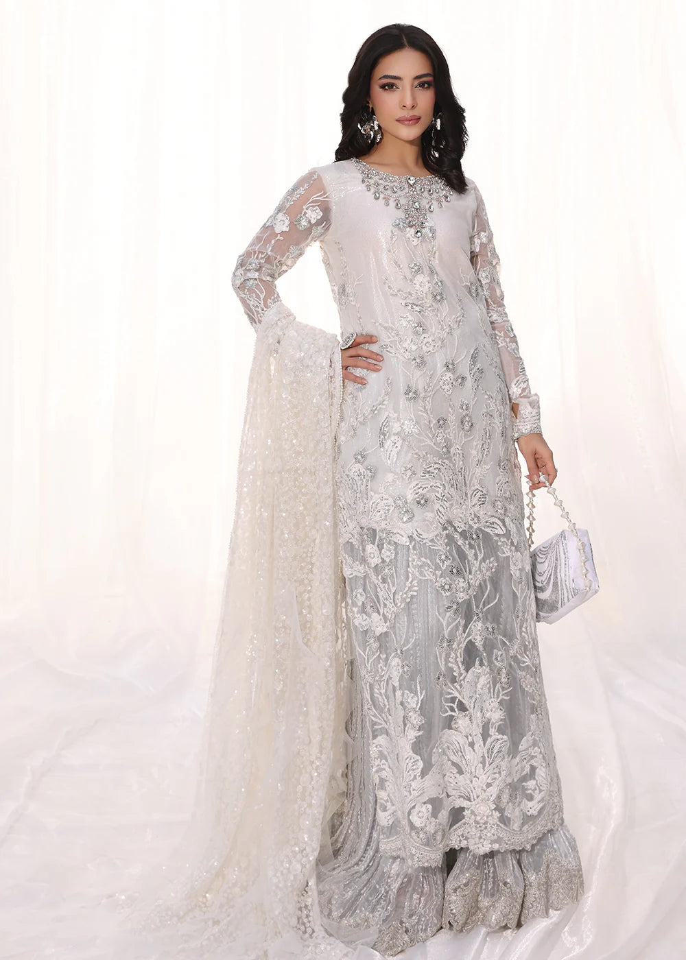 Model wearing silver and white embroidered dress with net dupatta from Musferah Saad Starlit, Pakistani Luxury pret available online in UK.
