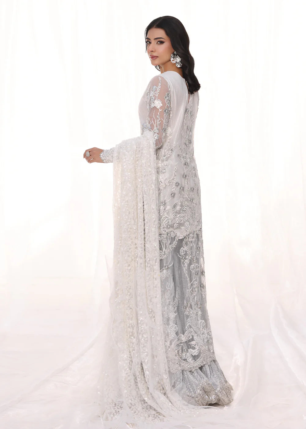 Model wearing silver and white embroidered dress with net dupatta from Musferah Saad Starlit, Pakistani Luxury pret available online in UK.