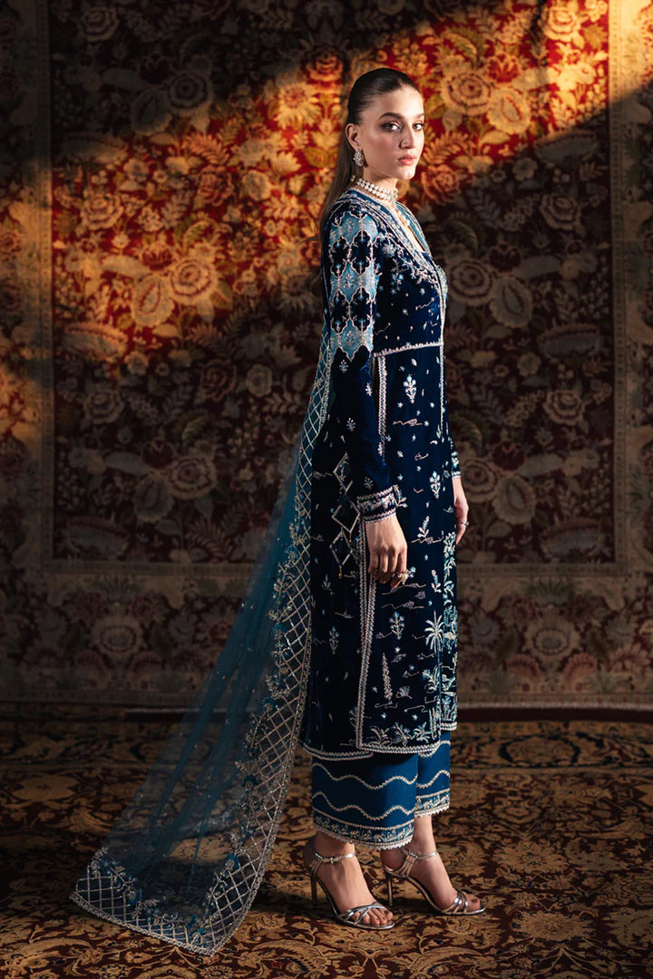 Model wearing Qalamkar Velvet Edit '24 BK-07 LIYANA, a deep blue velvet dress adorned with intricate embroidery, ideal for weddings. Available as Pakistani clothes online in the UK.