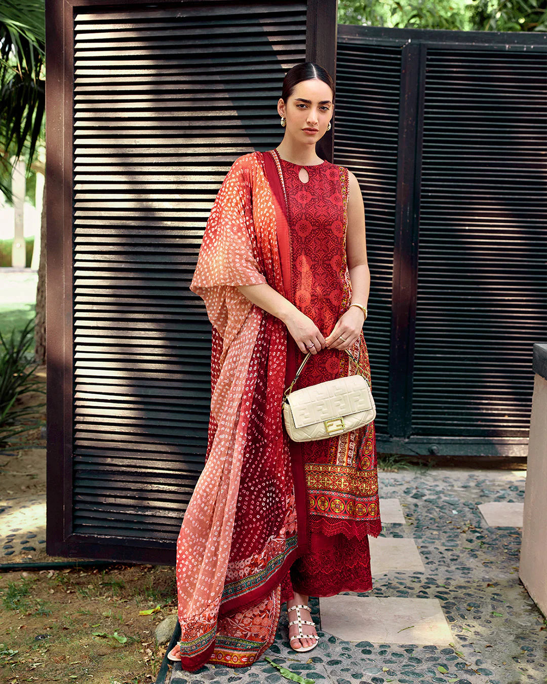 Model wearing Faiza Saqlain Carmela Gloriana dress in rich red with intricate patterns and a vibrant printed dupatta. Shop Pakistani bridal dresses online in the UK now.