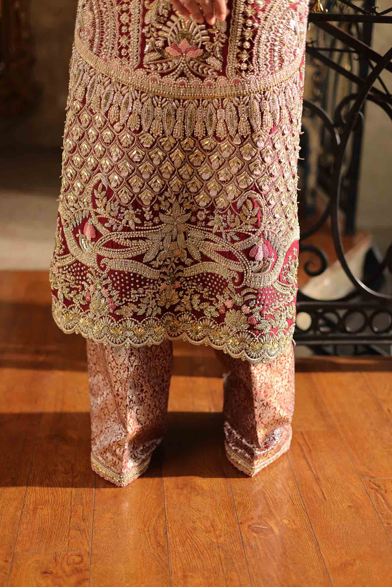 Model wearing deep maroon and gold hand-embellished long shirt with matching trousers from Mysie By Tahira Ruby, Pakistani Luxury pret UK.