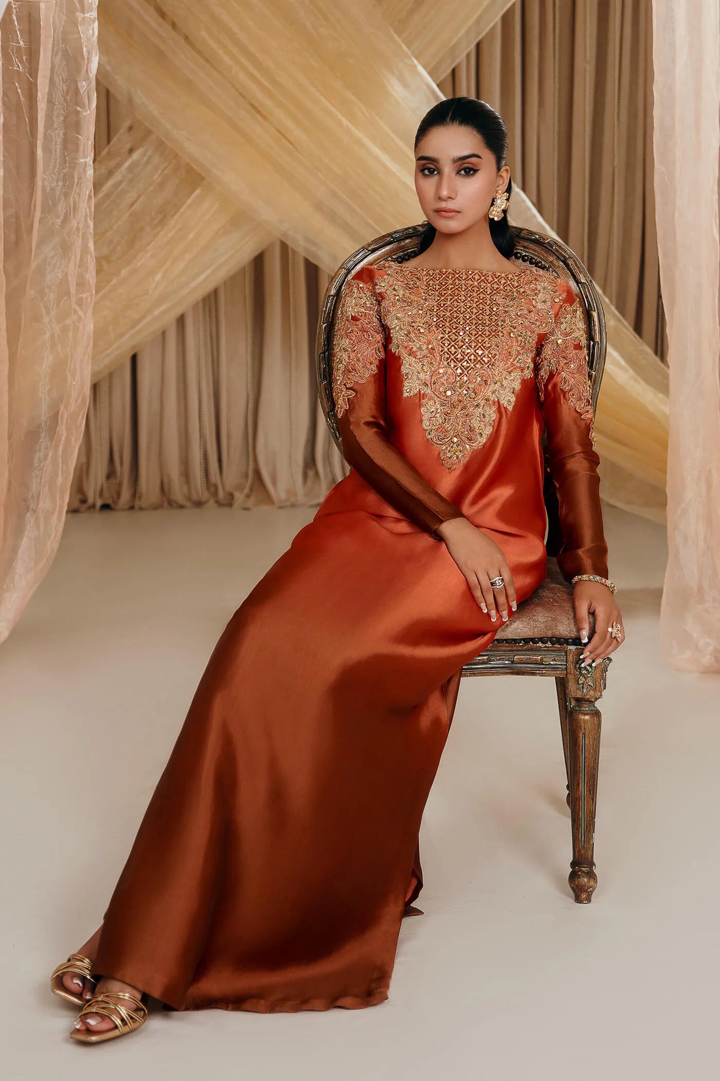 Model wearing Faiza Saqlain's Sunset Glow dress from the Musferah Saad Mystere Eid Collection '24. A stunning Pakistani Eid dress in burnt orange with intricate embroidery, ideal for Pakistani designer clothes lovers in the UK.