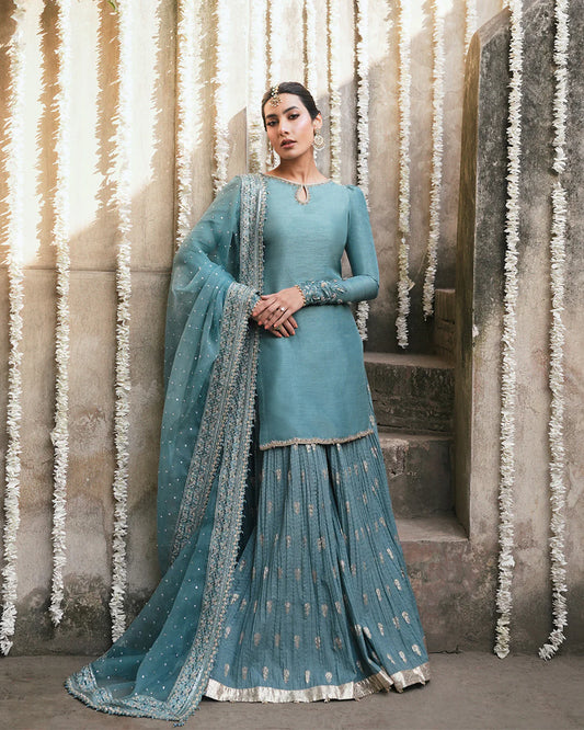 Model wearing teal blue Faiza Saqlain Tisha outfit with embellished dupatta and gharara, perfect for Pakistani luxury pret in UK.
