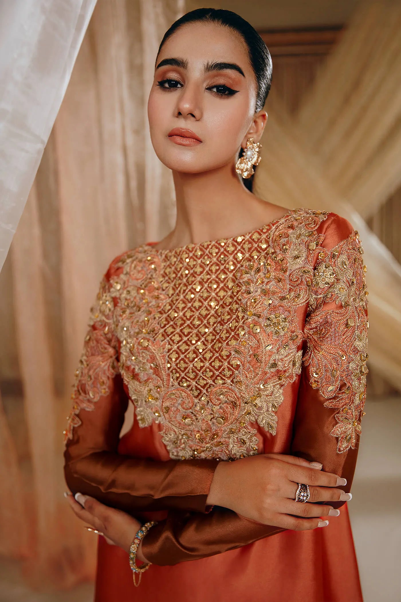 Model wearing Faiza Saqlain's Sunset Glow dress from the Musferah Saad Mystere Eid Collection '24. A stunning Pakistani Eid dress in burnt orange with intricate embroidery, ideal for Pakistani designer clothes lovers in the UK.