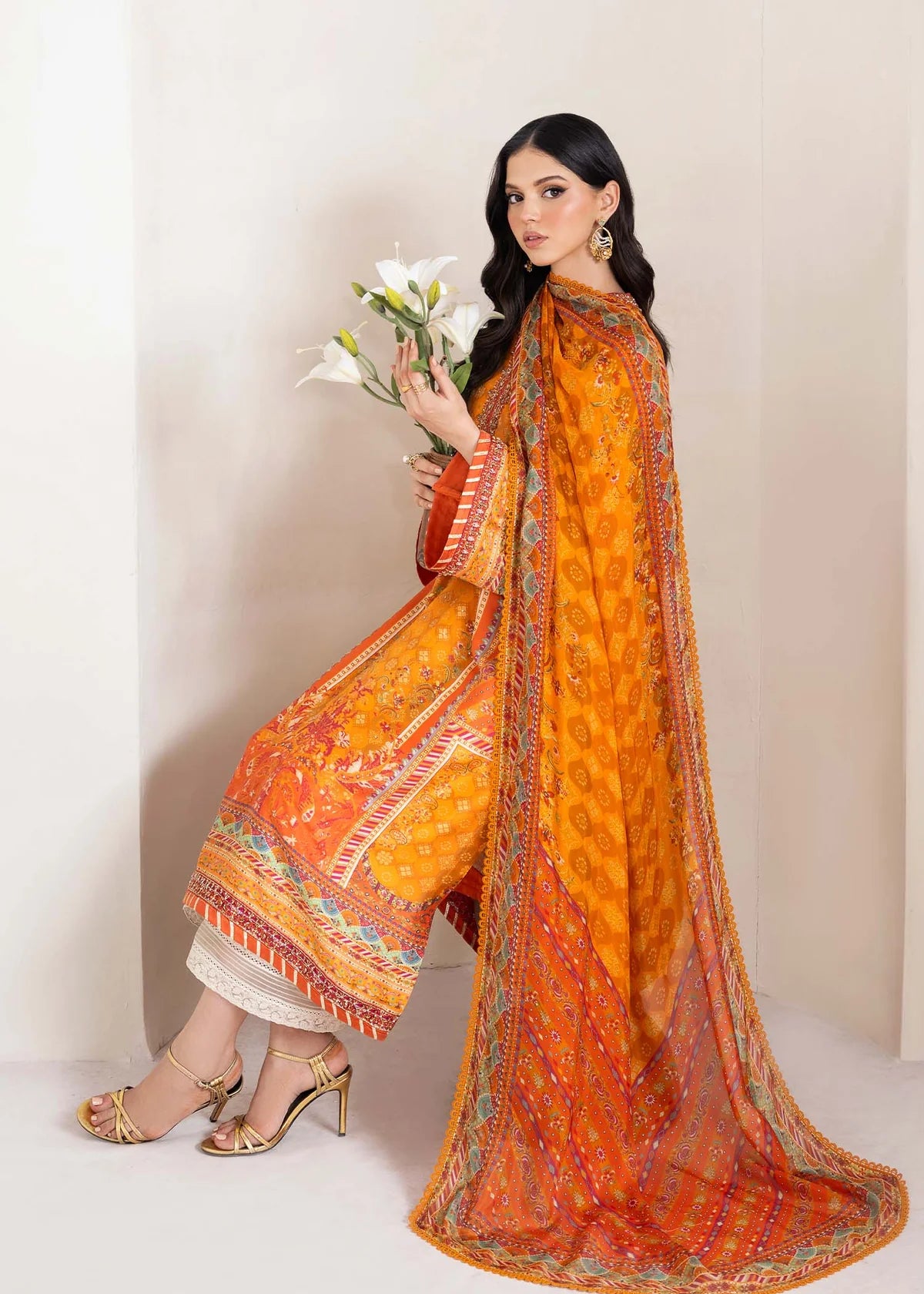 Model wearing bright orange printed Maesha from Kanwal Malik Rosalia Silk Eid Collection '25, Pakistani luxury pret online in UK.