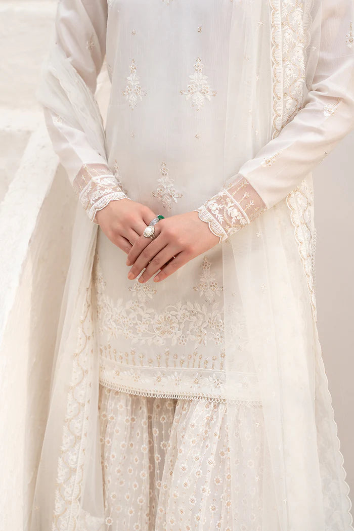 Model wearing Saira Rizwan Amaya dress, elegant white Pakistani clothes UK, detailed Eid wear.