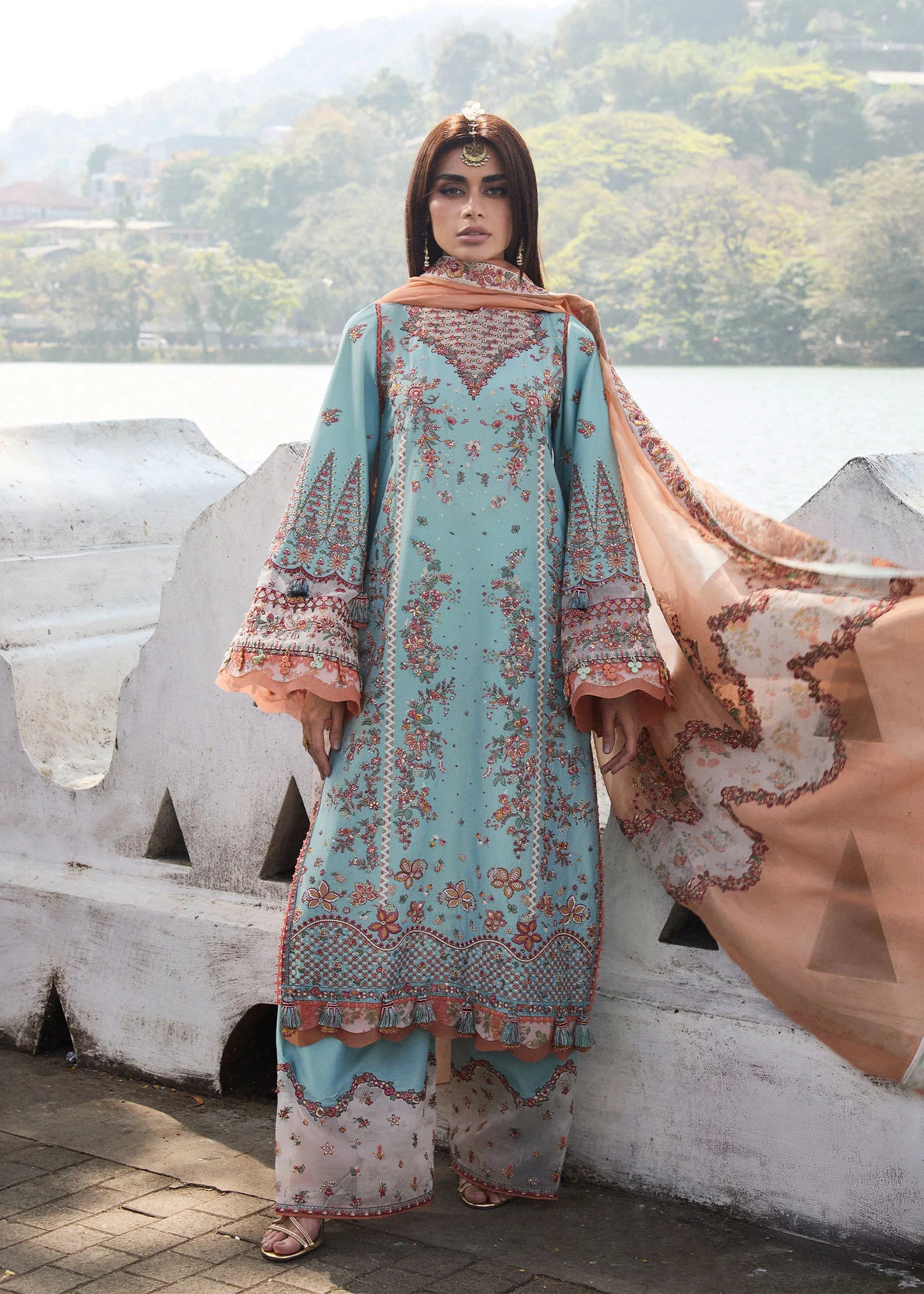 Model wearing Hussain Rehar Luxury Lawn '25 Malibu in turquoise blue with peach dupatta, intricate embroidery. Shop Pakistani luxury pret online in the UK.