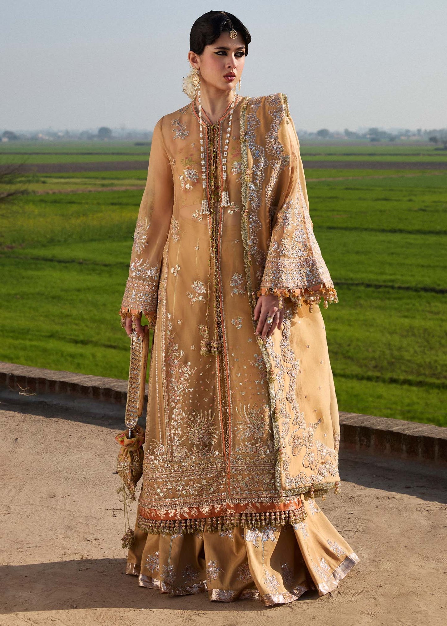 Model wearing Hussain Rehar Sundal golden beige embroidered festive dress with intricate embellishments and traditional details. Shop Pakistani clothes online in the UK now.