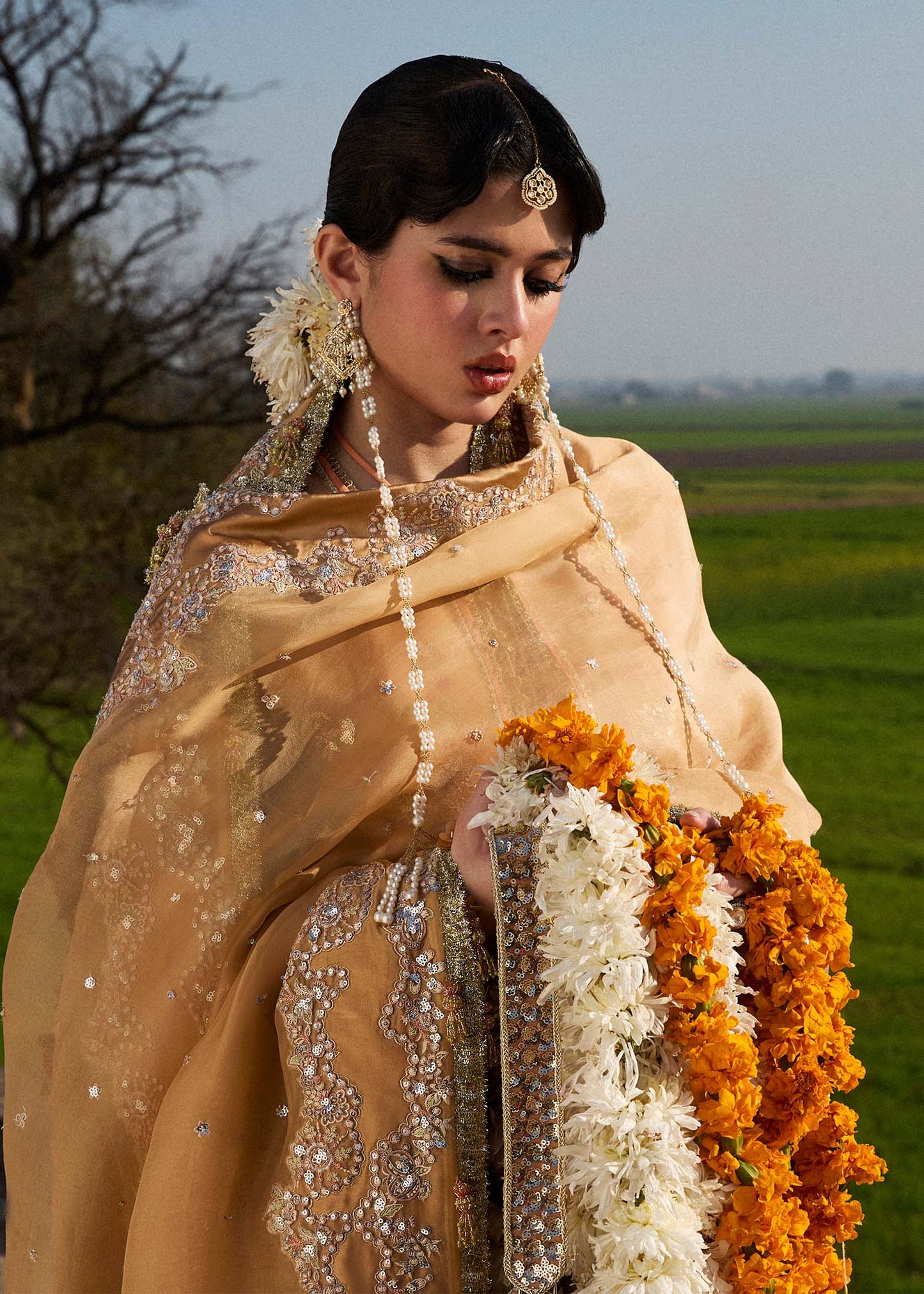 Model wearing Hussain Rehar Sundal golden beige embroidered festive dress with intricate embellishments and traditional details. Shop Pakistani clothes online in the UK now.