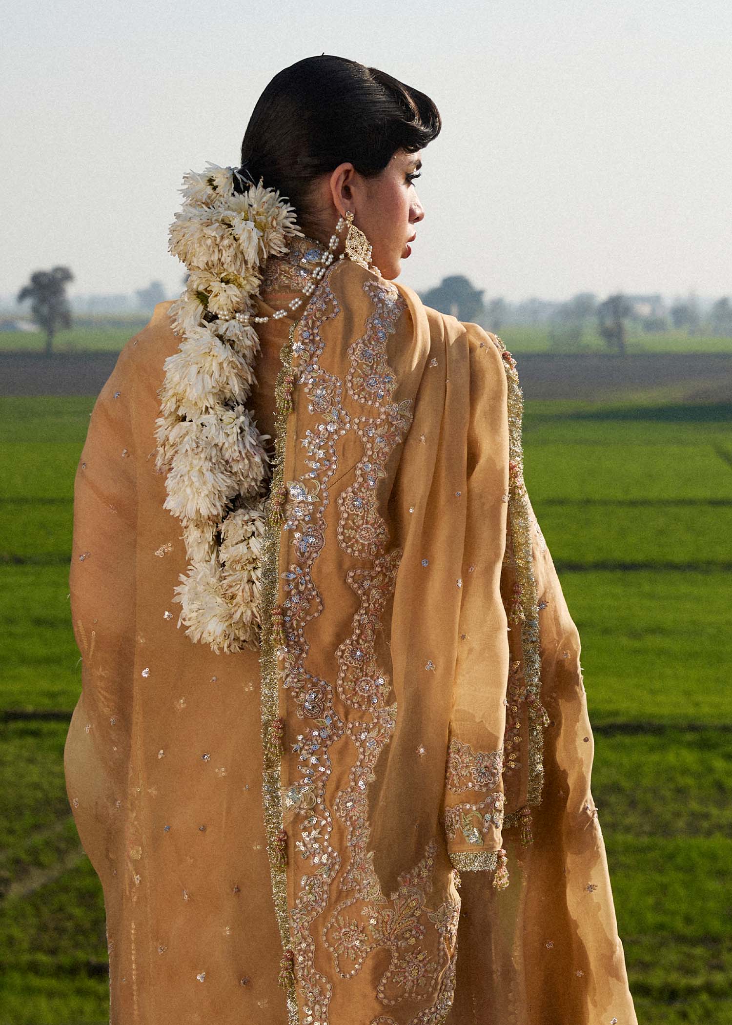 Model wearing Hussain Rehar Sundal golden beige embroidered festive dress with intricate embellishments and traditional details. Shop Pakistani clothes online in the UK now.