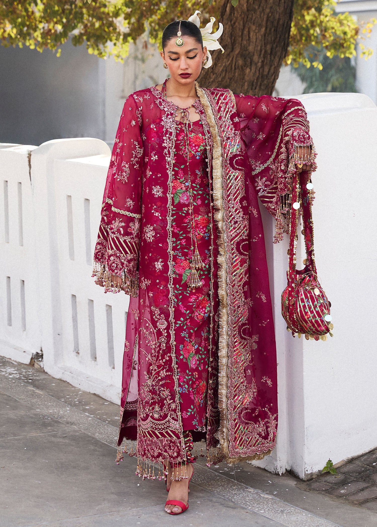 Model wearing Hussain Rehar Maher deep red embroidered festive dress with floral patterns and gold embellishments. Shop Pakistani clothes online in the UK now.