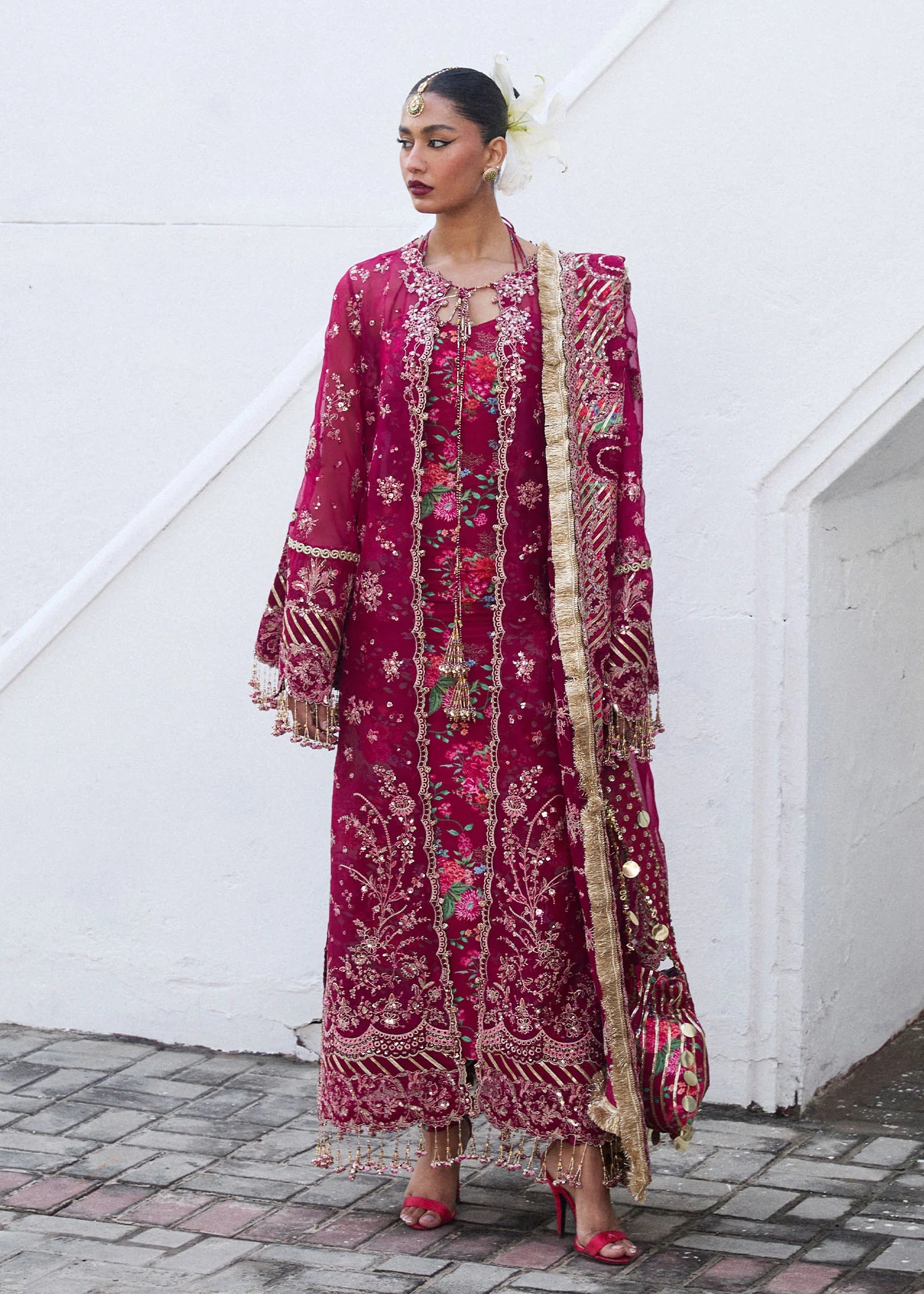 Model wearing Hussain Rehar Maher deep red embroidered festive dress with floral patterns and gold embellishments. Shop Pakistani clothes online in the UK now.