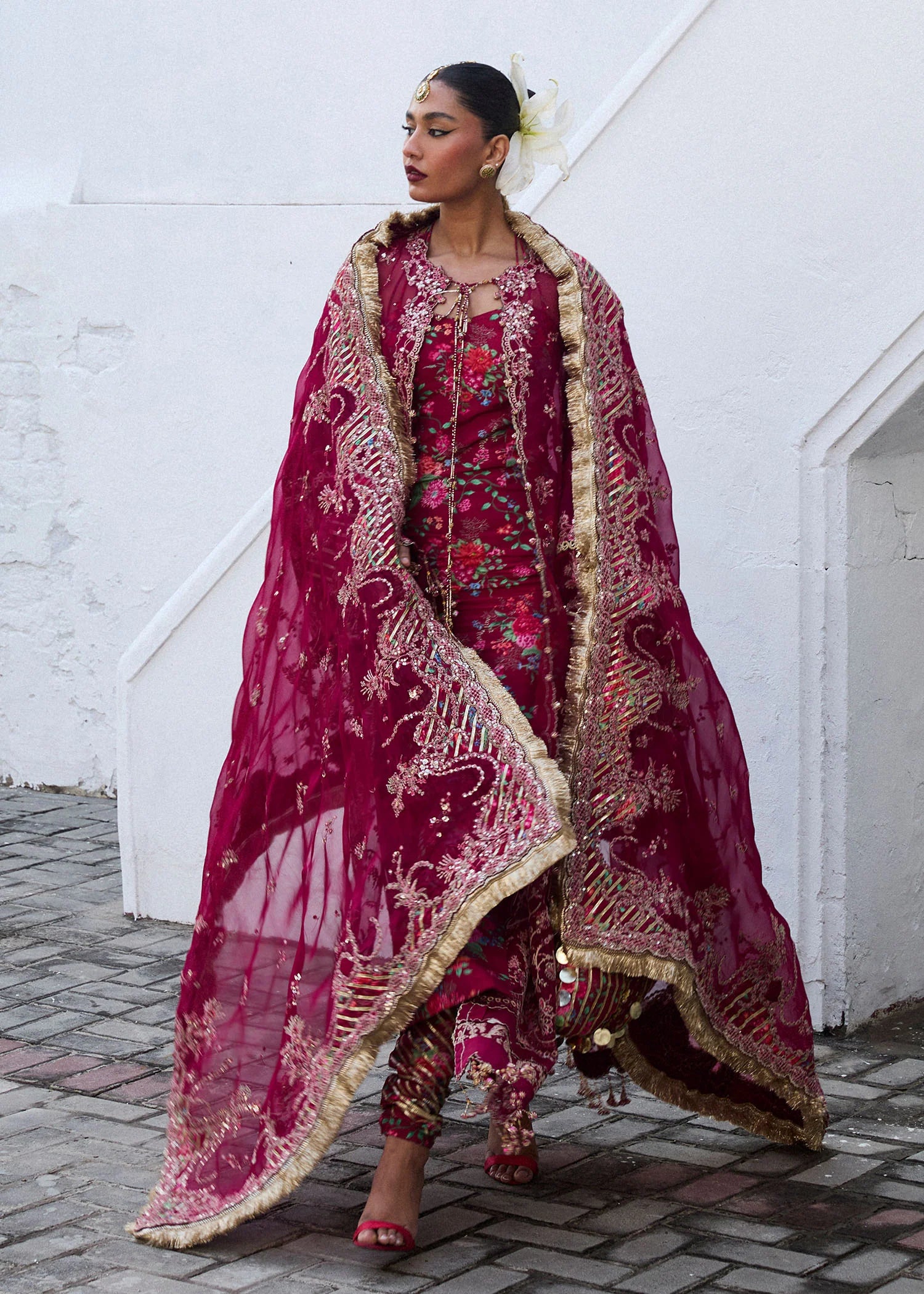 Model wearing Hussain Rehar Maher deep red embroidered festive dress with floral patterns and gold embellishments. Shop Pakistani clothes online in the UK now.