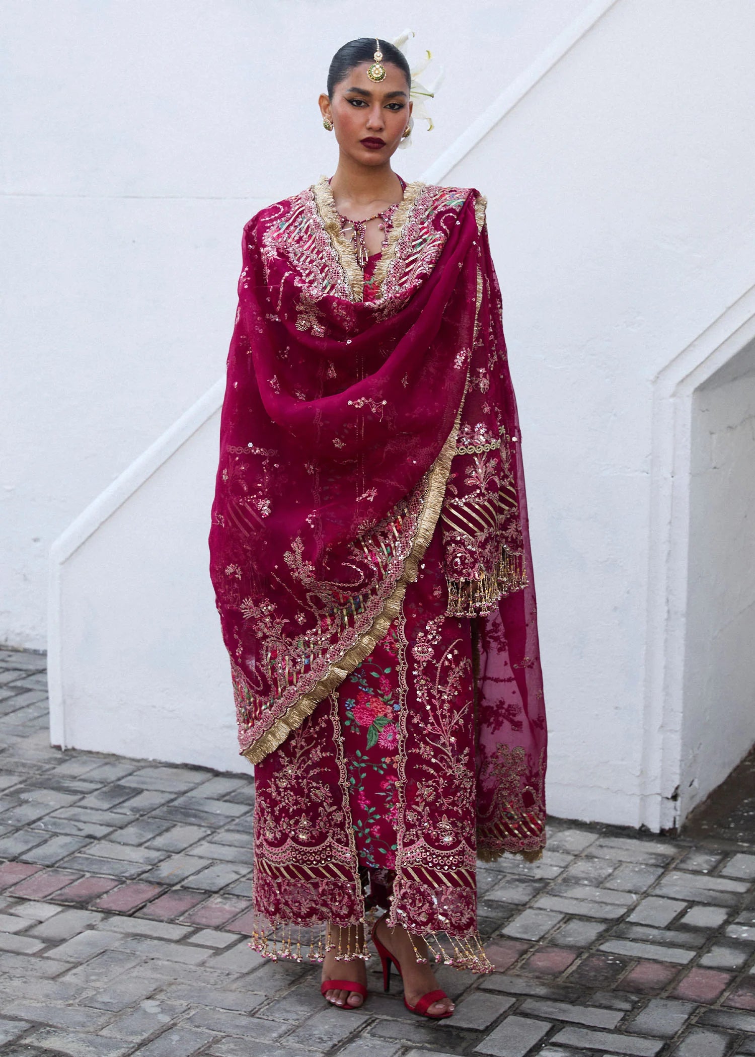 Model wearing Hussain Rehar Maher deep red embroidered festive dress with floral patterns and gold embellishments. Shop Pakistani clothes online in the UK now.