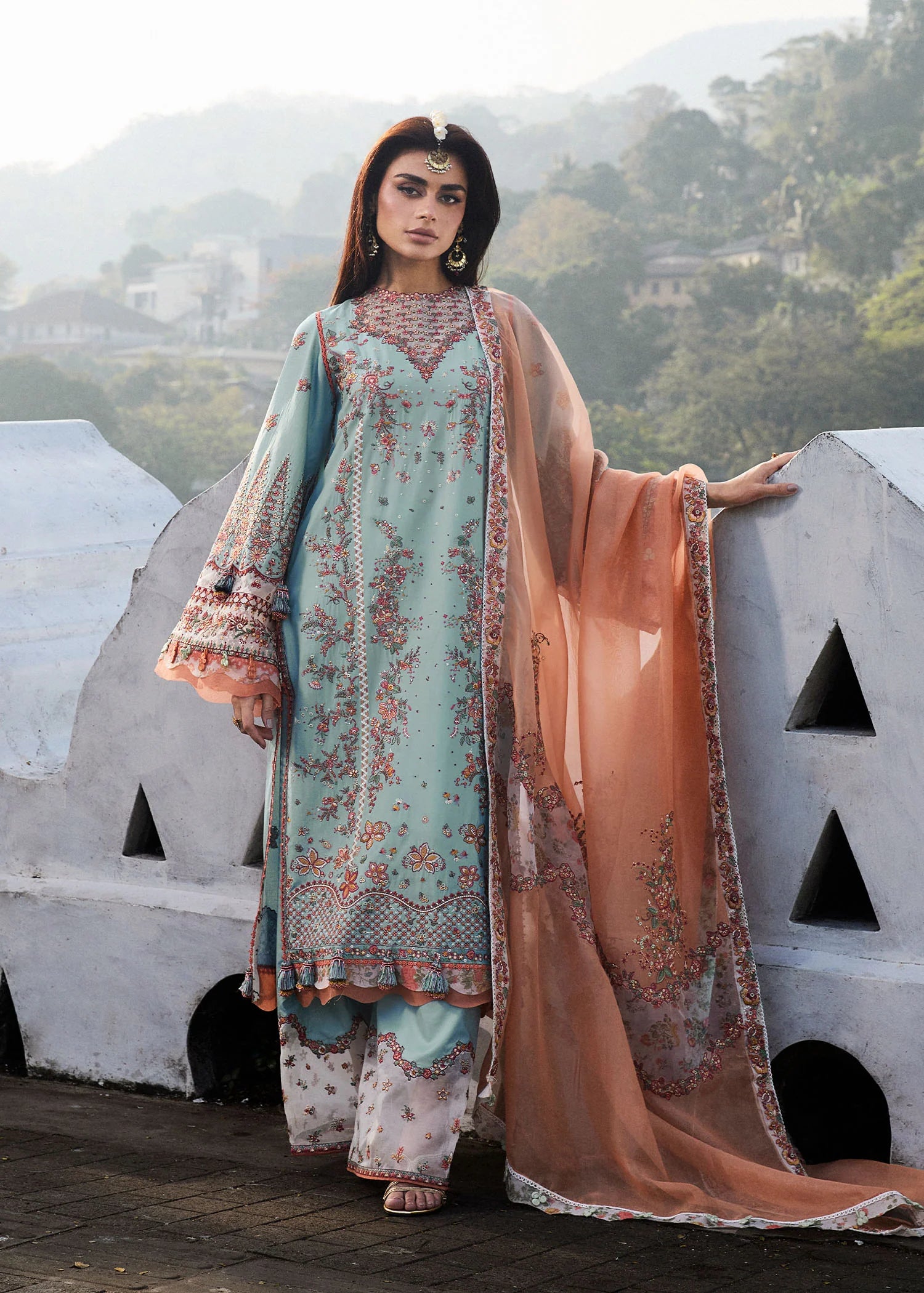 Model wearing Hussain Rehar Luxury Lawn '25 Malibu in turquoise blue with peach dupatta, intricate embroidery. Shop Pakistani luxury pret online in the UK.