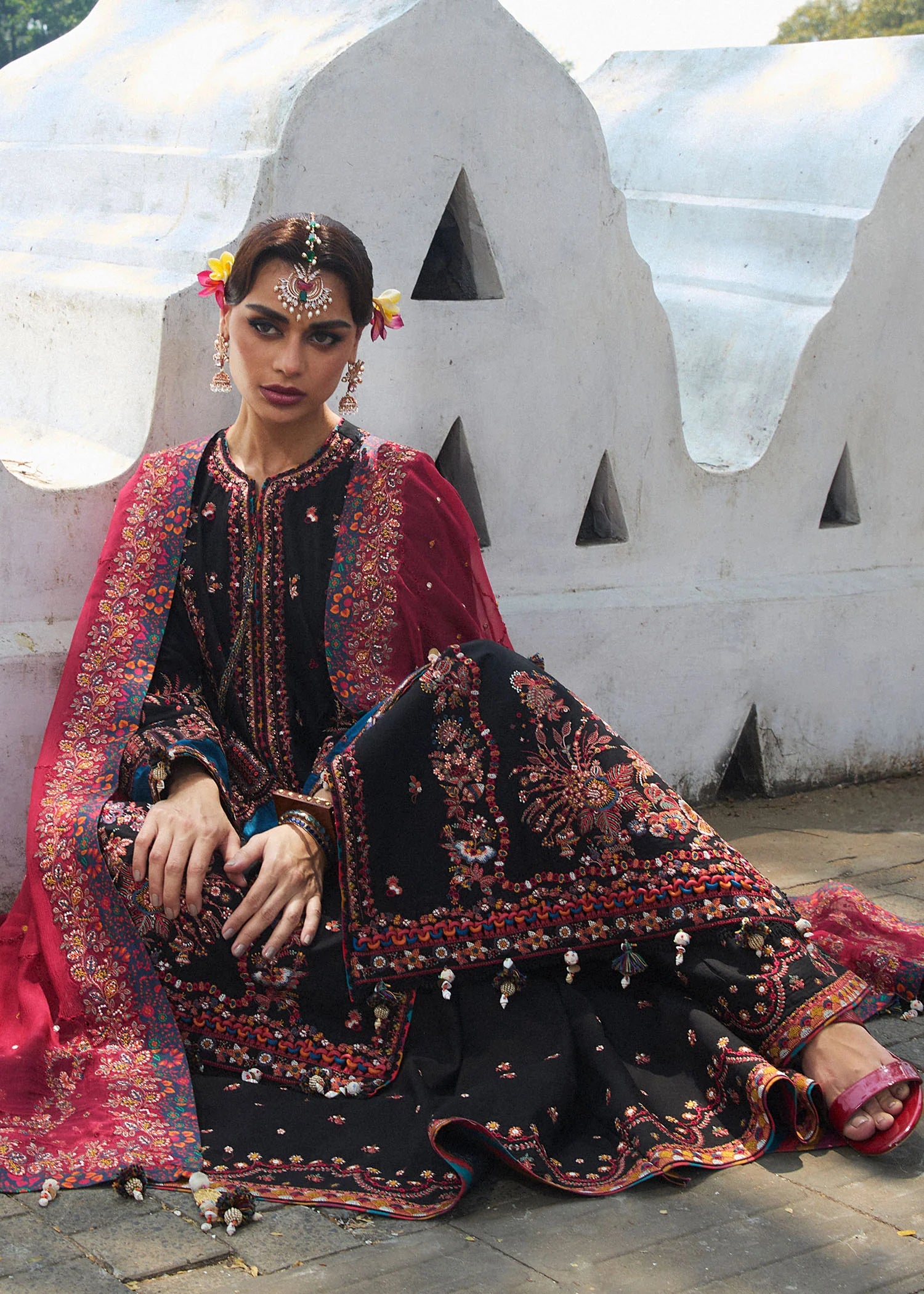 Model wearing Hussain Rehar Luxury Lawn '25 Bliz in black with intricate pink embroidery and a red dupatta. Shop Pakistani luxury pret online in the UK.