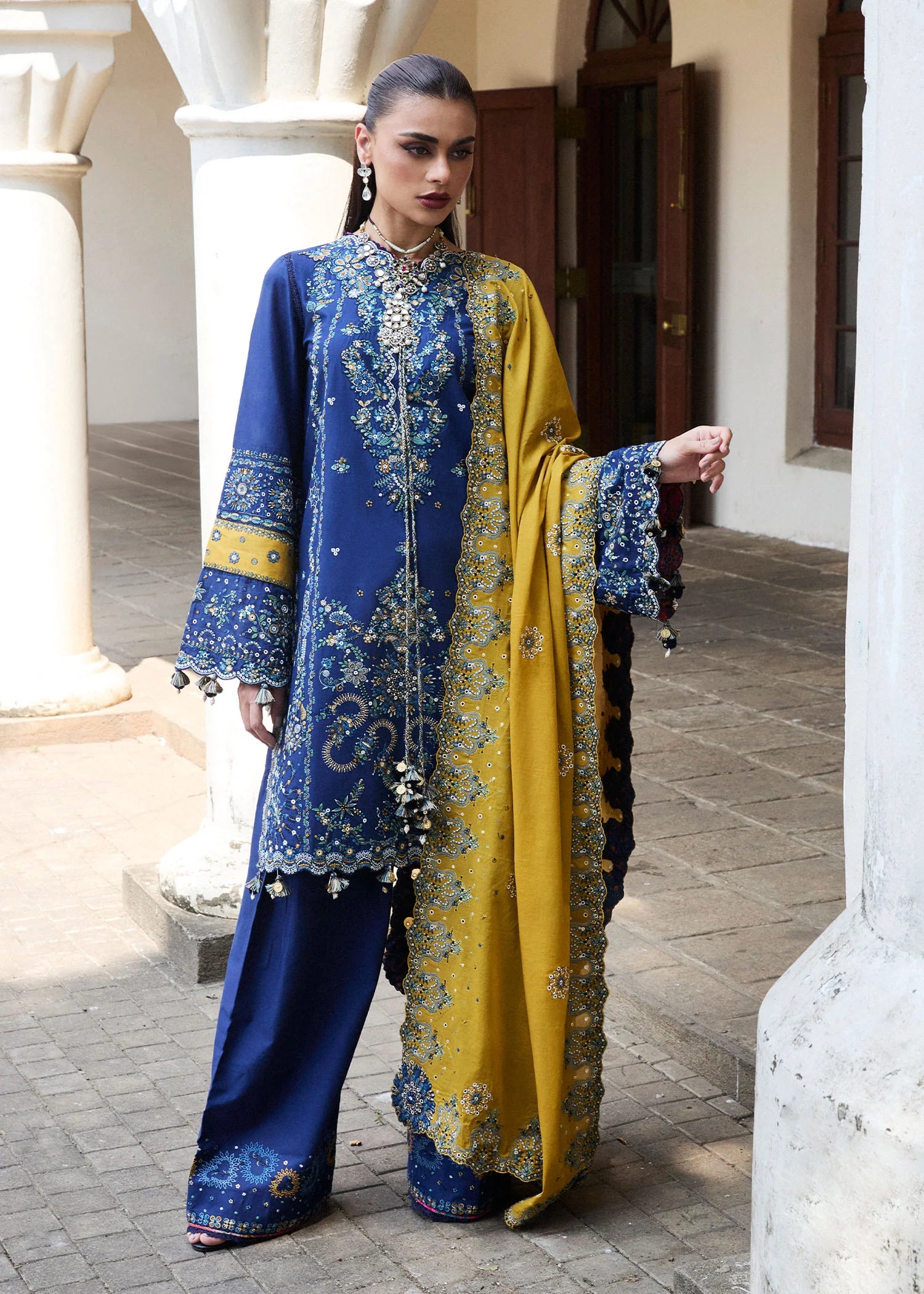 Model wearing Hussain Rehar Luxury Lawn '25 Riviera in royal blue with mustard dupatta, intricate embroidery. Shop Pakistani luxury pret online in the UK.