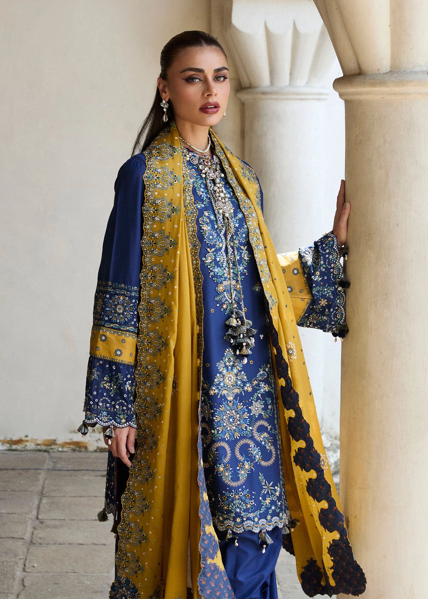 Model wearing Hussain Rehar Luxury Lawn '25 Riviera in royal blue with mustard dupatta, intricate embroidery. Shop Pakistani luxury pret online in the UK.