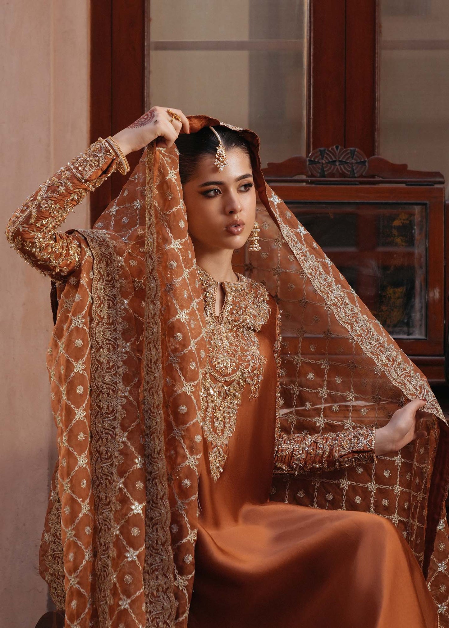 Model wearing Zulekha by Kanwal Malik in rust orange with gold embroidery – timeless Pakistani luxury pret available online in UK.