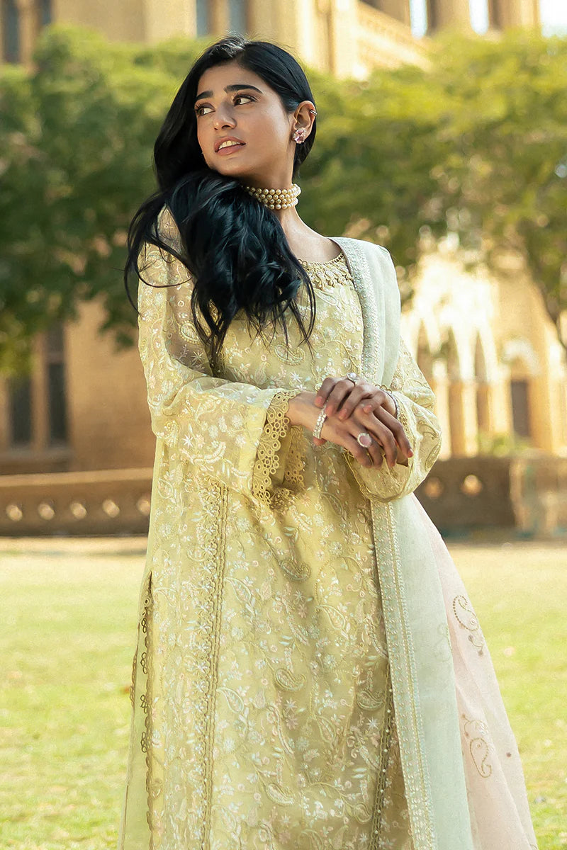 Model wearing Mushq Saugaat City of Lights Faryal in lime yellow with intricate embroidery and a white dupatta. Shop Pakistani luxury pret online in the UK.