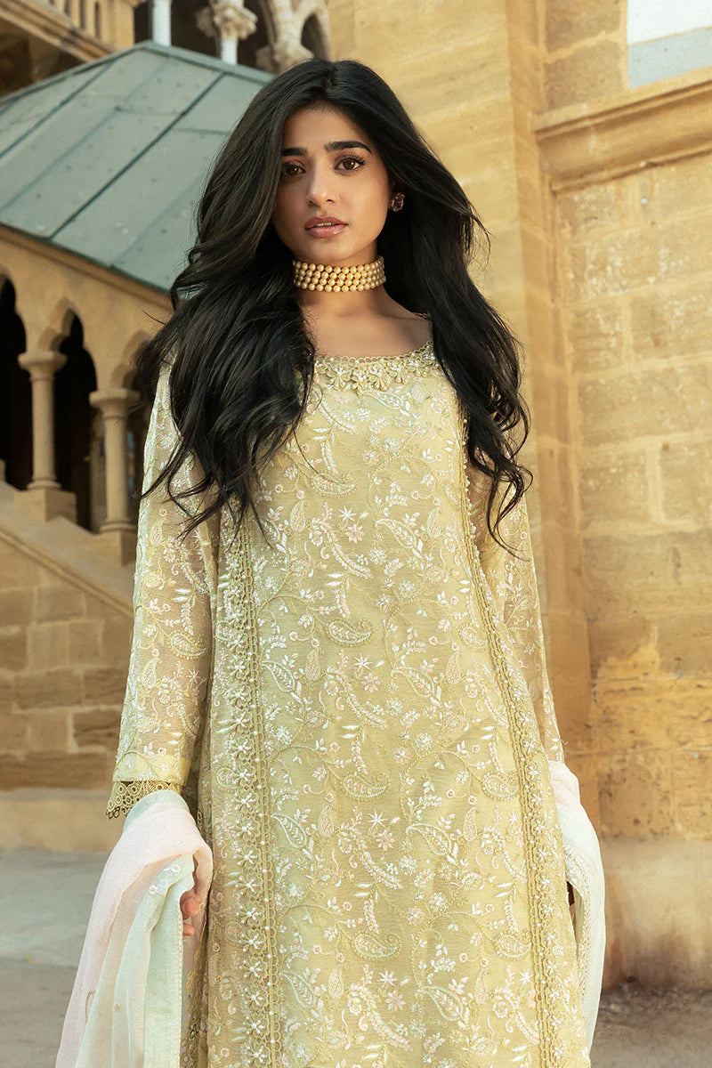 Model wearing Mushq Saugaat City of Lights Faryal in lime yellow with intricate embroidery and a white dupatta. Shop Pakistani luxury pret online in the UK.