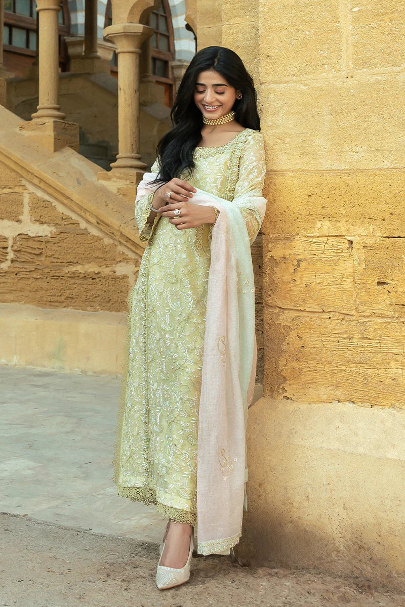 Model wearing Mushq Saugaat City of Lights Faryal in lime yellow with intricate embroidery and a white dupatta. Shop Pakistani luxury pret online in the UK.