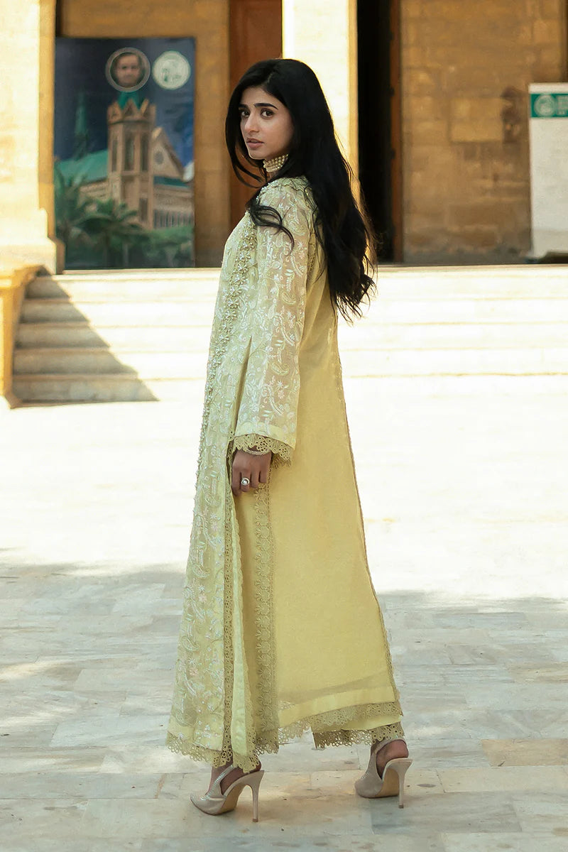 Model wearing Mushq Saugaat City of Lights Faryal in lime yellow with intricate embroidery and a white dupatta. Shop Pakistani luxury pret online in the UK.