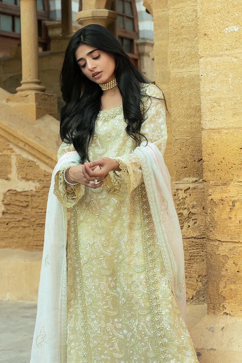 Model wearing Mushq Saugaat City of Lights Faryal in lime yellow with intricate embroidery and a white dupatta. Shop Pakistani luxury pret online in the UK.