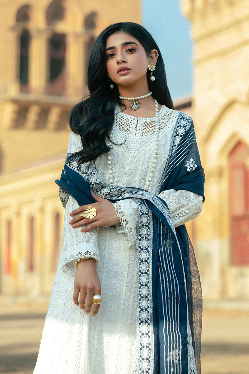 Model wearing Mushq Saugaat City of Lights Roshni in white with navy dupatta and lace details. Shop Pakistani luxury pret online in the UK.